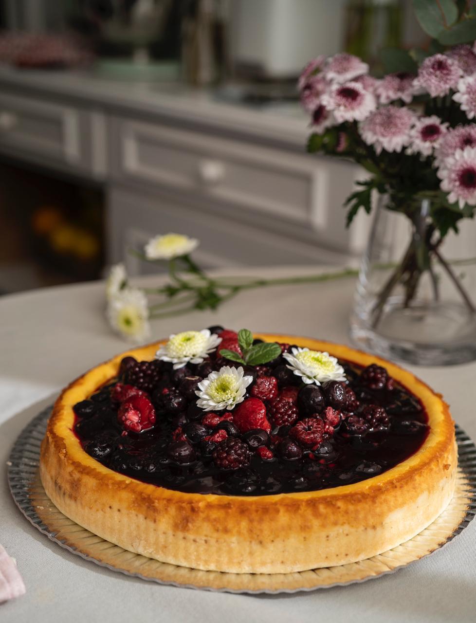 Tarta casera de frutos rojos decorada con flores en una mesa