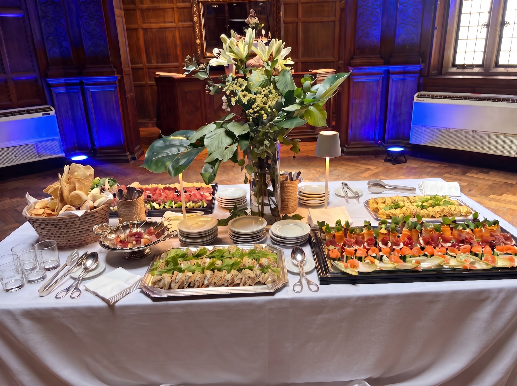 Mesa de evento con bocados, vajilla y flores en salón