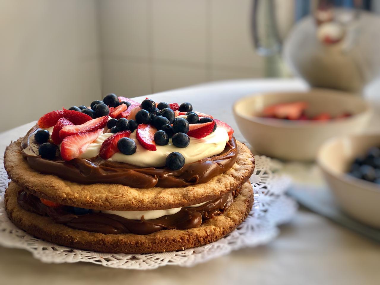 Torta casera de chocolate con crema, frutillas y arandanos