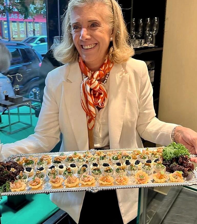 Clarisa vestida de blanco sonriendo con una bandeja de bocados