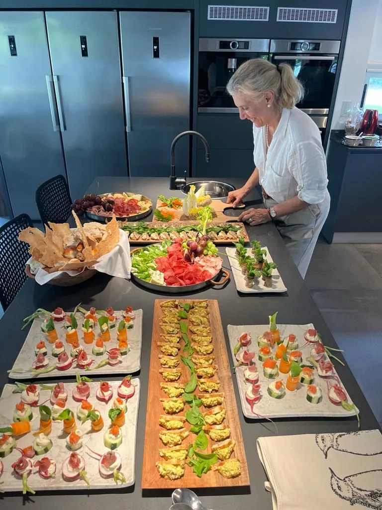 Clarisa preparando una mesa de catering con bocados, fiambres y panes