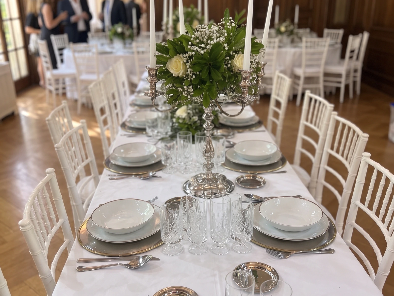 Mesa formal de celebración con vajilla blanca, flores y candelabros en salón